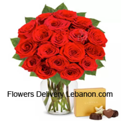 24 Trandafiri roșii cu câteva ferigi într-o vază de sticlă însoțiți de o cutie de ciocolată importată