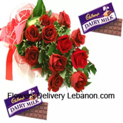 Kimppu 12 punaista ruusua sesonkikoristeiden kera sekä erilaisia Cadburyn suklaakonvehteja