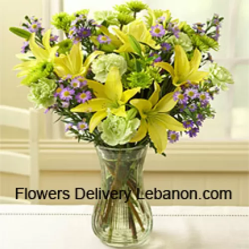 Żółte lilie i inne różne kwiaty ułożone pięknie w szklanej wazie