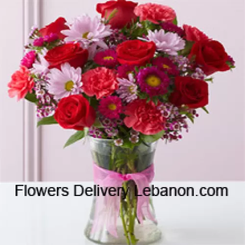 Czerwone róże, czerwone goździki i inne różnorodne kwiaty ułożone pięknie w szklanej wazie