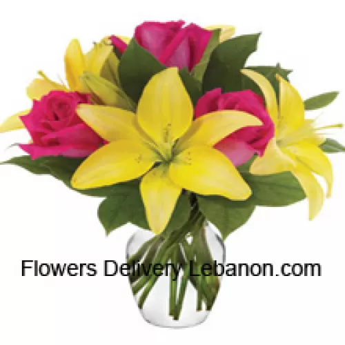Róże różowe i lilie żółte z dodatkiem sezonowych wypełniaczy uroczo ułożone w szklanym wazonie