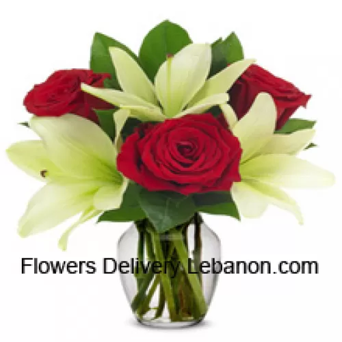 Crvene ruže i bijeli ljiljani s sezonskim punilima u staklenoj vazi