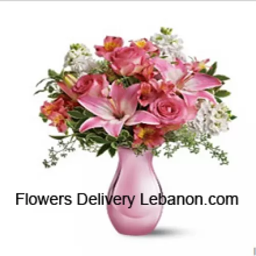 Vaaleanpunaiset ruusut, vaaleanpunaiset liljat ja erilaisia valkoisia kukkia muutamilla saniaisilla lasimaljakossa