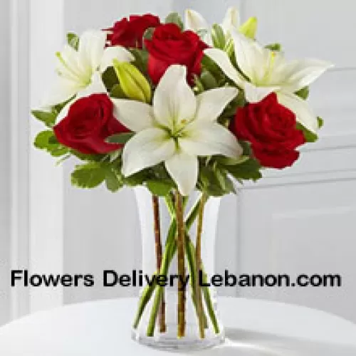 Czerwone Róże i Białe Lilie z dodatkiem kilku sezonowych wypełniaczy w szklanym wazonie