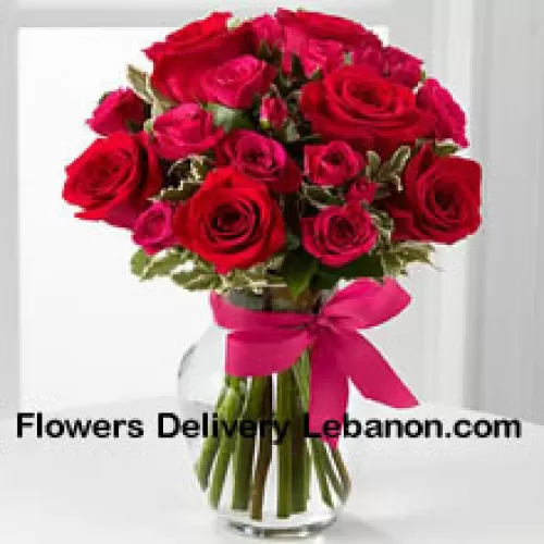 18 rote Rosen mit saisonalen Füllern in einer Glasvase, dekoriert mit einer rosa Schleife