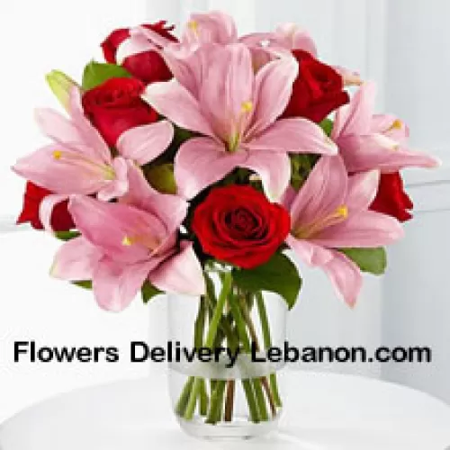 Красные розы и розовые лилии с сезонными наполнителями в стеклянной вазе