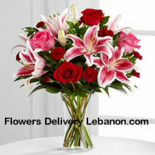 Punaisia ja vaaleanpunaisia ruusuja vaaleanpunaisilla liljoilla ja sesonkikoristeilla lasimaljakossa